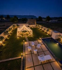 an outdoor event with a tent and chairs and a pool at 4j Aravalli Farms in Dhauj