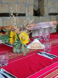 a table with a red table cloth with flowers and glasses at Къща за гости Българа in Vetren +40 photos