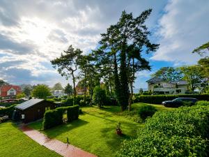 a yard with green grass and trees and houses at Ferienhaus Hugo in Lubmin