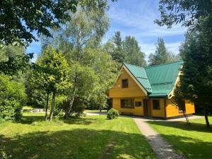 a yellow house with a green roof at Chata ALPINA 1 in Tatranská Lomnica