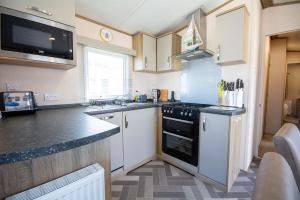 a kitchen with white cabinets and a black stove top oven at Sea View Lodge in Nefyn +23 photos