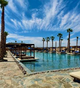 a swimming pool with palm trees and a blue sky at Agafay Oryx Camp in Aït Mazou