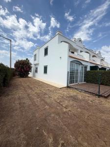 a white building with a dirt yard in front of it at Sunset Ria in Tavira
