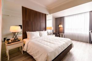 a bedroom with a large bed with a wooden headboard at Rich Palace Hotel in Surabaya