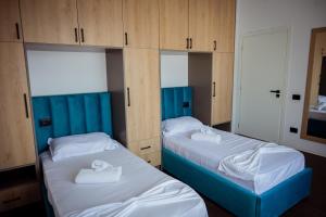 two beds in a room with wooden cabinets at Rooftop Apartment with Garden and Jacuzzi in Durrës