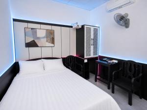 a bedroom with a bed and a desk with a fan at The Luxe Homestay in Buôn Ðũng