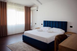 a bedroom with a large bed with a blue headboard at Rooftop Apartment with Garden and Jacuzzi in Durrës