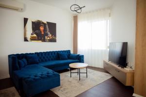 a living room with a blue couch and a tv at Rooftop Apartment with Garden and Jacuzzi in Durrës +24 photos