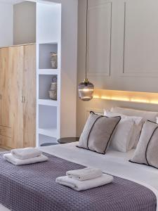 a white bedroom with two towels on a bed at Sunset Rocks Residence in Parasporos