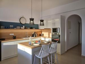 a kitchen with two bar stools and a clock on the wall at Sunset Rocks Residence in Parasporos