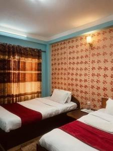 a room with two beds and a wall with wallpaper at Hotel New Bhojpure in Kathmandu