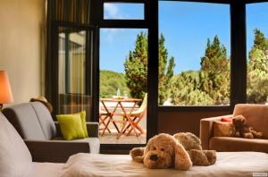 un osito de peluche sentado en una cama en una sala de estar en H+ Hotel Willingen, en Willingen 62 fotos más