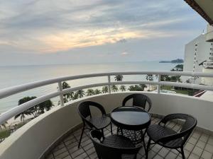 a balcony with chairs and a table and the ocean at Tanjung Tuan Beach Regency - Hermis Theme 1 Car Park in Kampong Baharu