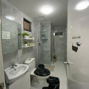 a bathroom with a toilet and a sink and a shower at Mely's Condotel Mactan in Mactan Island +1 photo