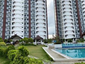 a large apartment building with a swimming pool in front of it at Mely's Condotel Mactan in Mactan Island