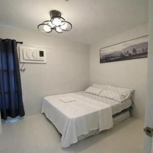 a small bedroom with a bed and a ceiling fan at Mely's Condotel Mactan in Mactan Island