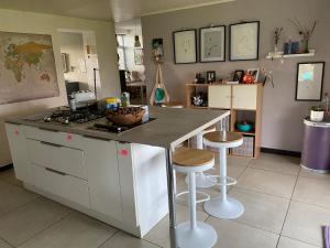 a kitchen with a counter with a stove and stools at Maison de campagne in Chièvres