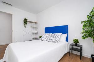 a white bedroom with a white bed with a blue headboard at Jouvacations Villa Sol La Selva in Vilafant +13 photos