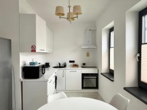 a small white kitchen with white cabinets and a table at DREAM HOUSE Apartaments in Bistriţa