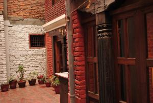 an entrance to a brick building with potted plants at Yamba Traditional Home in Pātan