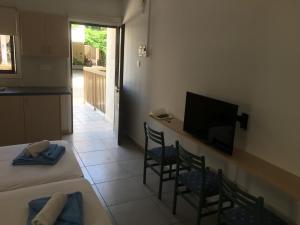 a room with a bed and chairs and a television at Mandali Court in Ayia Napa