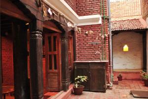 un bâtiment en briques avec une porte en bois et une plante en pot dans l'établissement Yamba Traditional Home, à Pātan