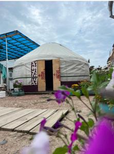 a large tent in a yard with purple flowers at "AlmUrUt" Guest House in Bokonbayevo +13 photos