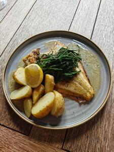 a plate of food with fish and potatoes and a lemon at The Plough Itchen Abbas in Winchester