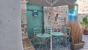 a patio with two tables and chairs and an umbrella at Cavo Paradise Studio Cyclades in Kimolos