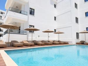 a swimming pool with chairs and umbrellas next to a building at Avenue by Deserve in Paphos