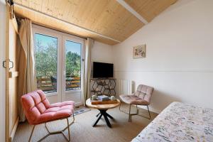 a bedroom with a bed and two chairs and a tv at Maison d'hôtes Au Cocon de Verdure in Châteauneuf