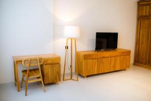 a room with a desk and a television and a chair at JeKa Escotel & Loft in Seminyak