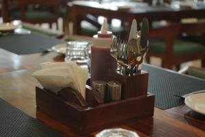 a wooden holder with utensils and a candle on a table at Hotel Tavijay in Jhunjhunūn