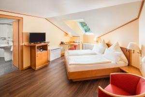 a hotel room with a bed and a television at Hotel Asemann Planegg in Planegg