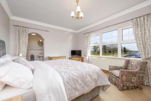 a bedroom with a bed and a chair and windows at Turner's Corner by Escape Ordinary in Aghadowey