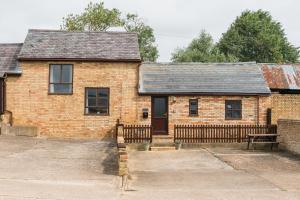 a brick house with a wooden fence in front of it at Cottage 2 at Scald end cottages in Bedford