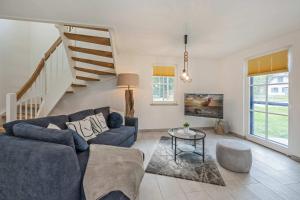 a living room with a blue couch and a staircase at Fischerdorf Ferienhaus JoHann in Zirchow