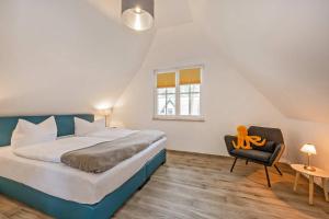 a bedroom with a bed and a chair and a window at Fischerdorf Ferienhaus JoHann in Zirchow