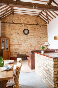 a living room with a brick wall and a clock at Cottage 2 at Scald end cottages in Bedford +18 photos