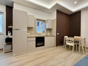 a kitchen with white cabinets and a table with chairs at Cagrovi Apartments in Casoria