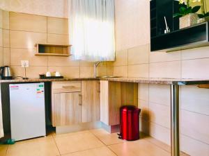 a kitchen with a white refrigerator and a red trash can at Radiant Resort in Manzini