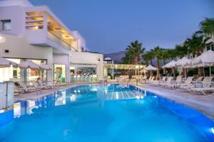 a pool with chairs and umbrellas in front of a building at Angela Suites Boutique Hotel in Sisi