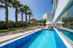 a swimming pool with palm trees and a building at Angela Suites Boutique Hotel in Sisi
