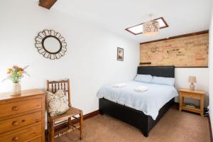a bedroom with a bed and a chair and a mirror at Cottage 2 at Scald end cottages in Bedford