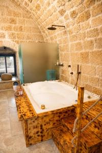 a bathroom with a large tub in a stone wall at האבן והים - סוויטה מדהימה עם ג'קוזי בעיר העתיקה עכו in Acre +25 photos
