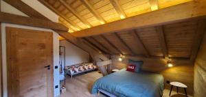 a bedroom with a bed and a wooden ceiling at Le BÔ Chalet - Jacuzzi et Sauna - 3 chambres in Anould