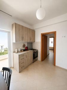 a kitchen with wooden cabinets and a large window at Velmare apartments in Paralia Vrachou