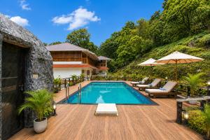 a swimming pool on a wooden deck next to a house at Soma Seven Springs Resort in Munnar