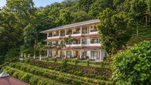 a large white house on a hill with trees at Soma Seven Springs Resort in Munnar