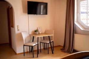 a small table with two chairs and a television on the wall at Landhaus Schneeberg AusZeit am Küppel & Bright Collection in Gersfeld